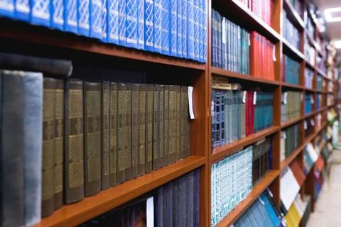 Blurred image of a library with bookcases. Many different books on the shelves Stock Photos