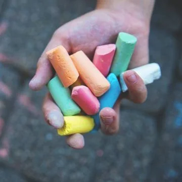 Blurred image Multi-colored colored chalk in a child's hand close-up. The con Stock Photos