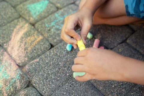 Blurred image Multi-colored colored chalk in a child's hand close-up. Stock Photos