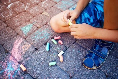 Blurred image Multi-colored colored chalk in a child's hand close-up. Stock Photos