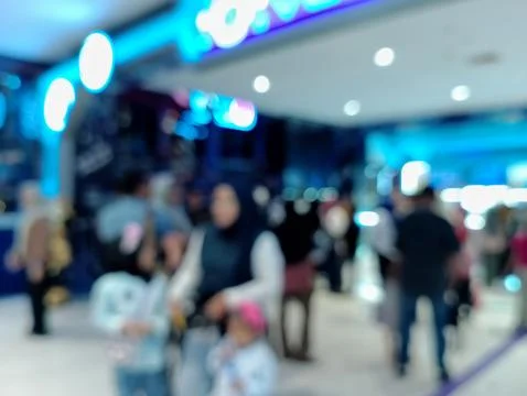 A blurred image of numerous people inside a bright, indoor space. The lightin Stock Photos