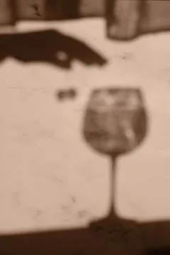 Blurred image of the shadow of a wine glass and a womans hand Stock Photos