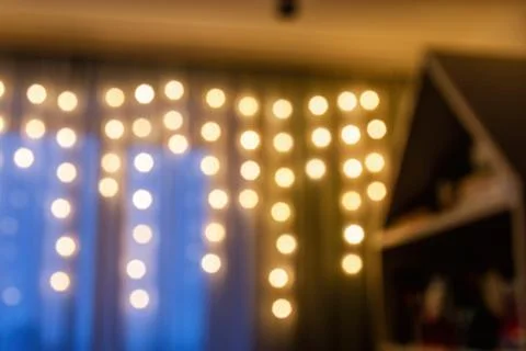 Blurred image of warm, inviting bokeh lights strung across a curtain Stock Photos