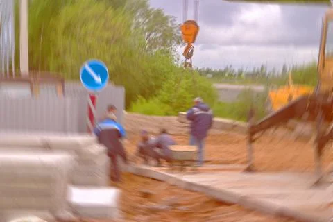 Blurred image of workers using a crane laid concrete slabs for the road. Stock Photos