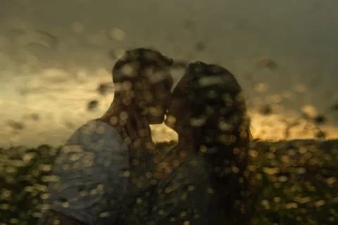Blurred image of a young couple guy and girl kissing on the lips at sunset in Stock Photos