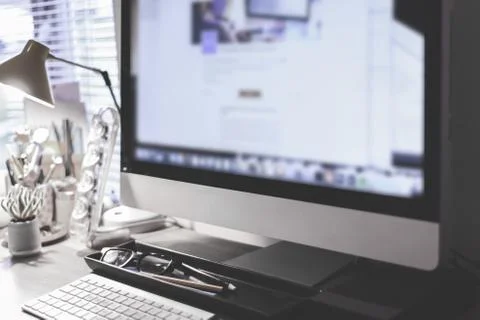 Blurred large computer screen on a home office desk interior eith work object Stock Photos