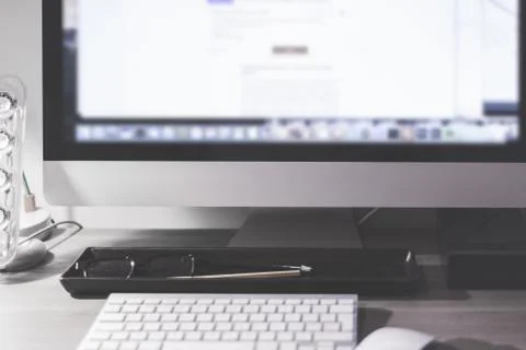 Blurred large computer screen on a home office desk interior eith work object Stock Photos