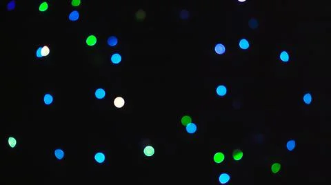 Blurred light of small colored bulbs on black background. Stock Photos
