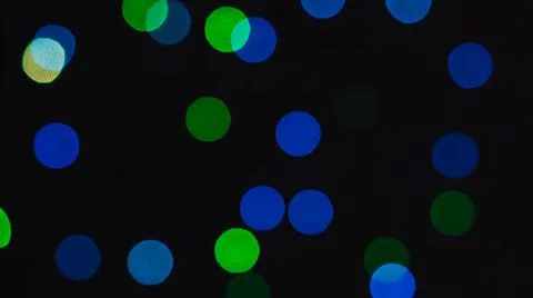 Blurred light of small colored bulbs on black background. Stock Photos
