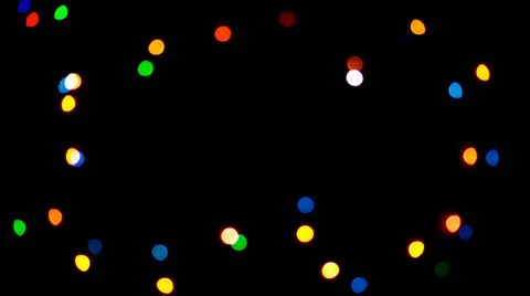 Blurred light of small colored bulbs on black background. Stock Photos