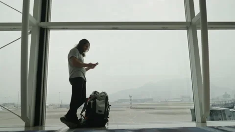 Blurred long haired hispanic man chatting with his phone while an airplane is Stock Footage 227687631