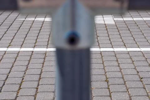 Blurred metal pipe on foreground. In the background, a white stripe on paveme Stock Photos