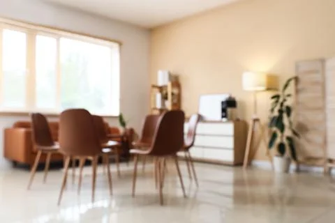 Blurred modern office interior with empty chairs and sofa, bright window ligh Stock Photos