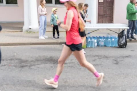 Blurred motion of a female runner in red sportswear during an outdoor race. Stockfoto's