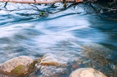 Blurred Mountain River Flow between Fallen Birch Tree Trunk and Big Boulders. Stock Photos