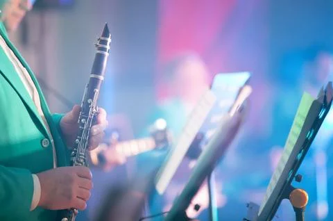 A blurred musical background in which hands hold a saxaphone in front of a st Foto stock