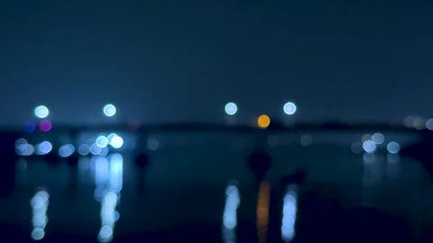 Blurred night cityscape with glowing lights reflecting on calm water under .. Stock Footage 340220849