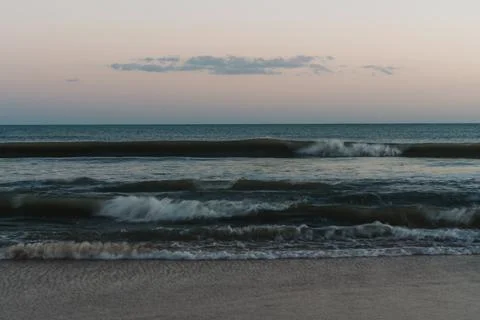 Blurred ocean waves in soft blue and pink hues during twilight. Stock Photos