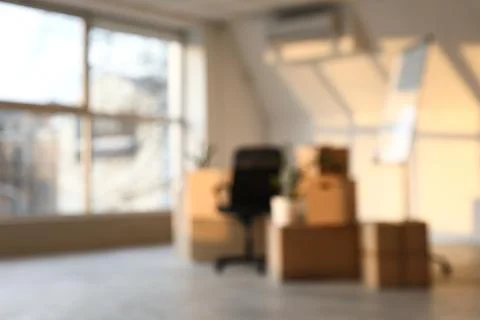 Blurred office interior with moving boxes and desk chair, relocation and busi Stock Photos