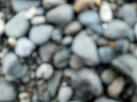 Blurred or defocused abstract background of smooth small rocks on black sand Stock Photos