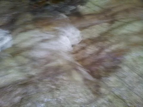 Blurred or unfocused view of flowing water stream in between stones Stock Photos