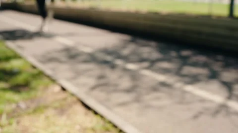 Blurred person running in slow motion on a cycle path in a park Vídeos de archivo 343044292