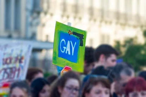 Blurred photo of marching crowd while holding a tablet 'gay' on a gay pride m Stock Photos