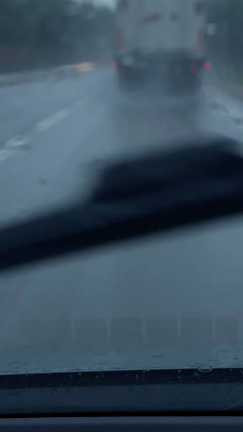 Blurred rainy road view through windshield with traffic ahead on wet city street Stock Footage 345764390