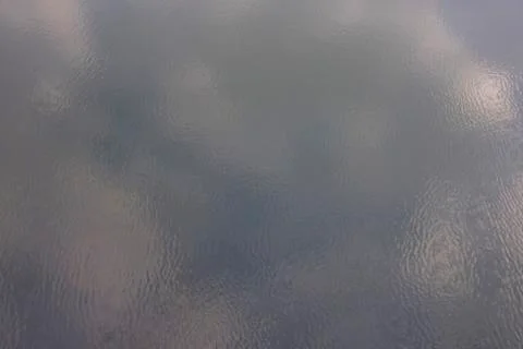 Blurred reflection of clouds on the surface of the water with light ripples. Stock Photos