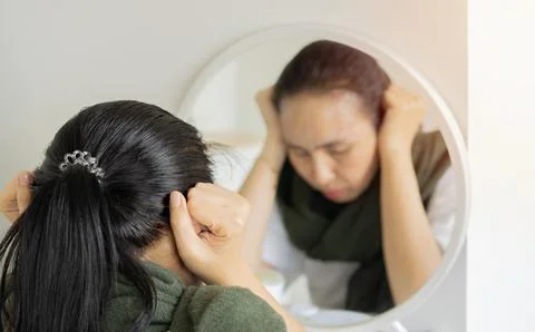 Blurred reflection in the mirror of sad and lonely Asian woman holding her .. Stock Photos