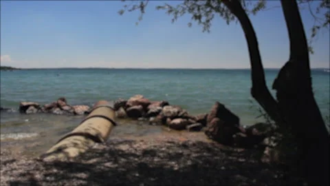 Blurred river with stones, rocks, waves and three, in Lazise, Garda Lake, Verona Video stock 132073571