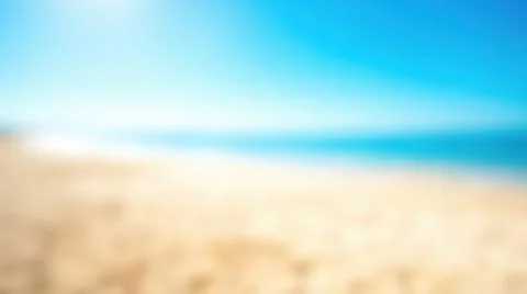 Blurred sandy beach blue ocean water clear sky empty coastline bright sunny.. Stock Photos