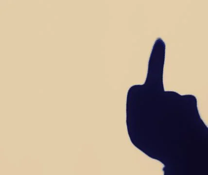 Blurred shadow of the middle finger on the painted wall, shadow of the middle Stock Photos