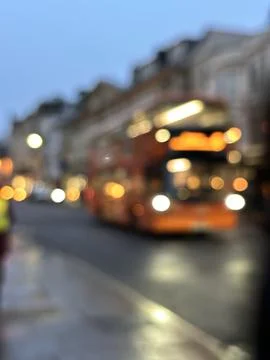 Blurred shot of a bus passing through city street, evening city lights glowin Stock Photos