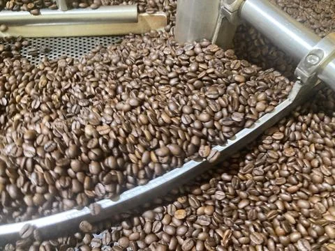 The blurred shot of the silver roaster machine is roasting coffee beans Stock Photos