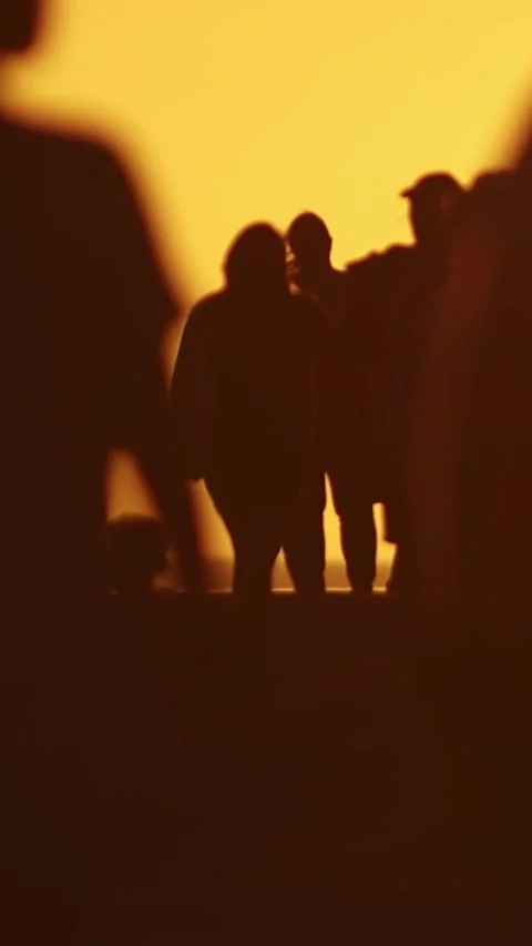 Blurred silhouettes of different people walking at orange sunset in slow motion Stock Footage 329971371
