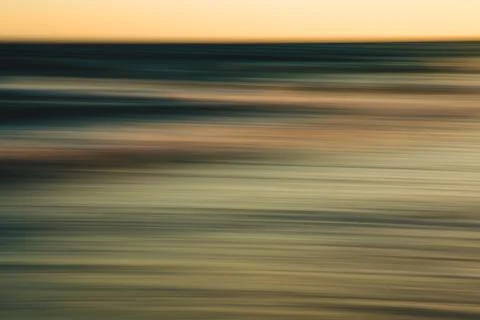 Blurred sunset reflection over the ocean with soft golden tones. Stock Photos