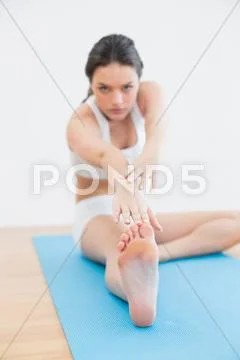 Blurred toned woman doing the hamstring stretch on exercise mat in fitness Stock Photos