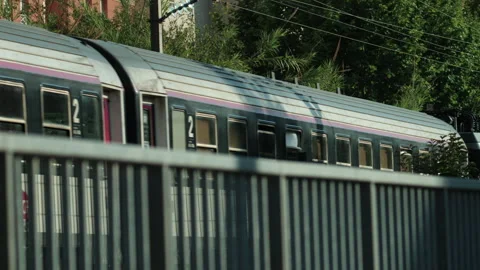 Blurred train moving fast in the city with a metal railing in the foreground and Stock Footage 339804465