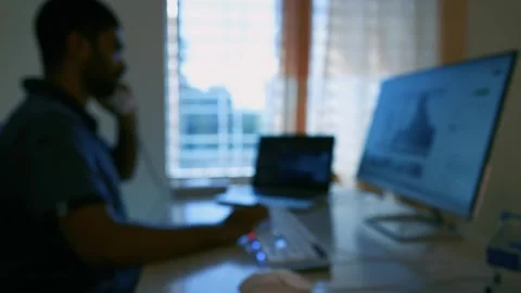 Blurred video of a person working at a computer desk with multiple screens Stock Footage 318056605