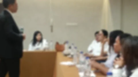 A blurred video of A speaker in a suit presents to an attentive audience seated Stock Footage 340533751
