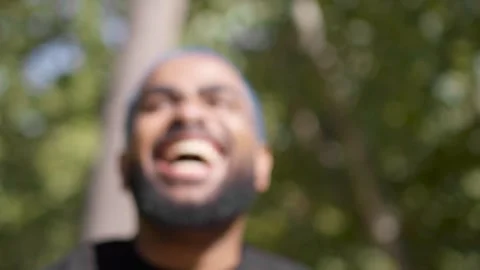 Blurred view of black man laughing joyful in a park while chatting Stock Footage 287488766