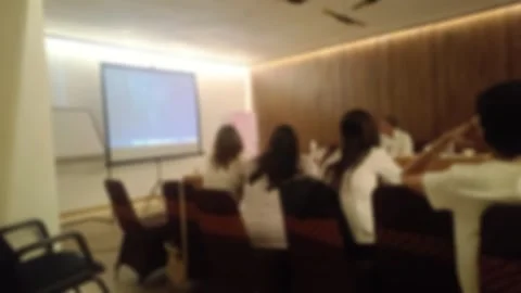A blurred view of a business meeting in progress, with attendees seated around a Stock Footage 340533756
