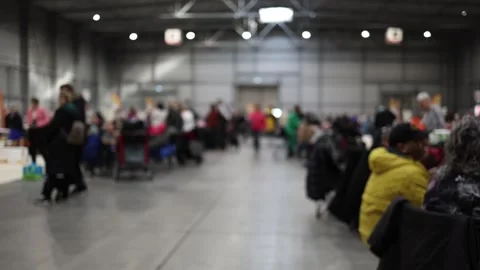 A blurred view of a busy indoor event with people engaged in various activities. Stock Footage 294780123