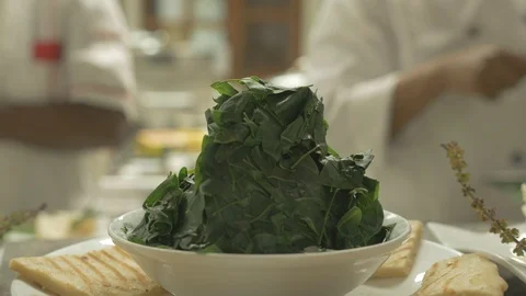Blurred view of chefs preparing food behind and a green salad on a bowel Stock Footage 109199346
