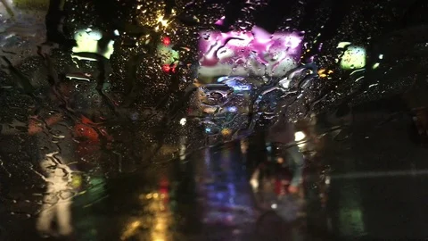 Blurred view of a city at night  through wet windscreen of a car in a rainy day Stock Footage 104842265