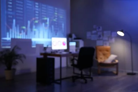 Blurred view of dark data scientist's office with workplace, glowing lamp and Foto stock