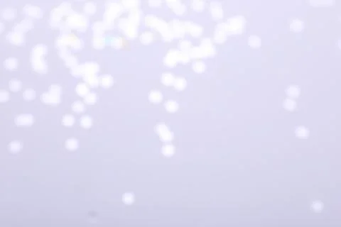 Blurred view of festive lights on light background. Bokeh effect Stock Photos