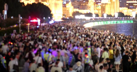 Blurred view of massive crowd of people walking along river embankment at night 動画素材 327649367
