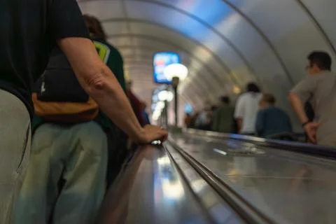 Blurred view up a metro escalator with commuters in urban underground station 库存照片